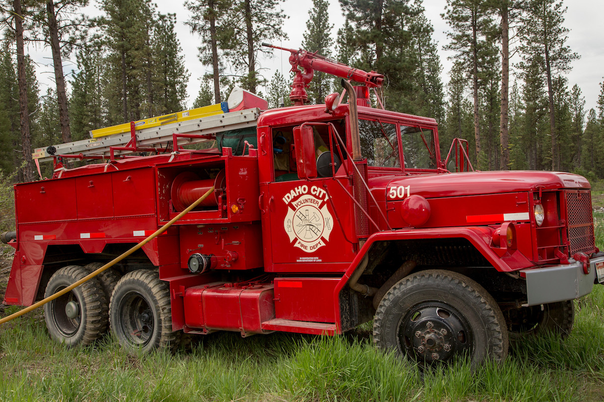 red fire engine parked in the grass displaying the Idaho City logo on the door.