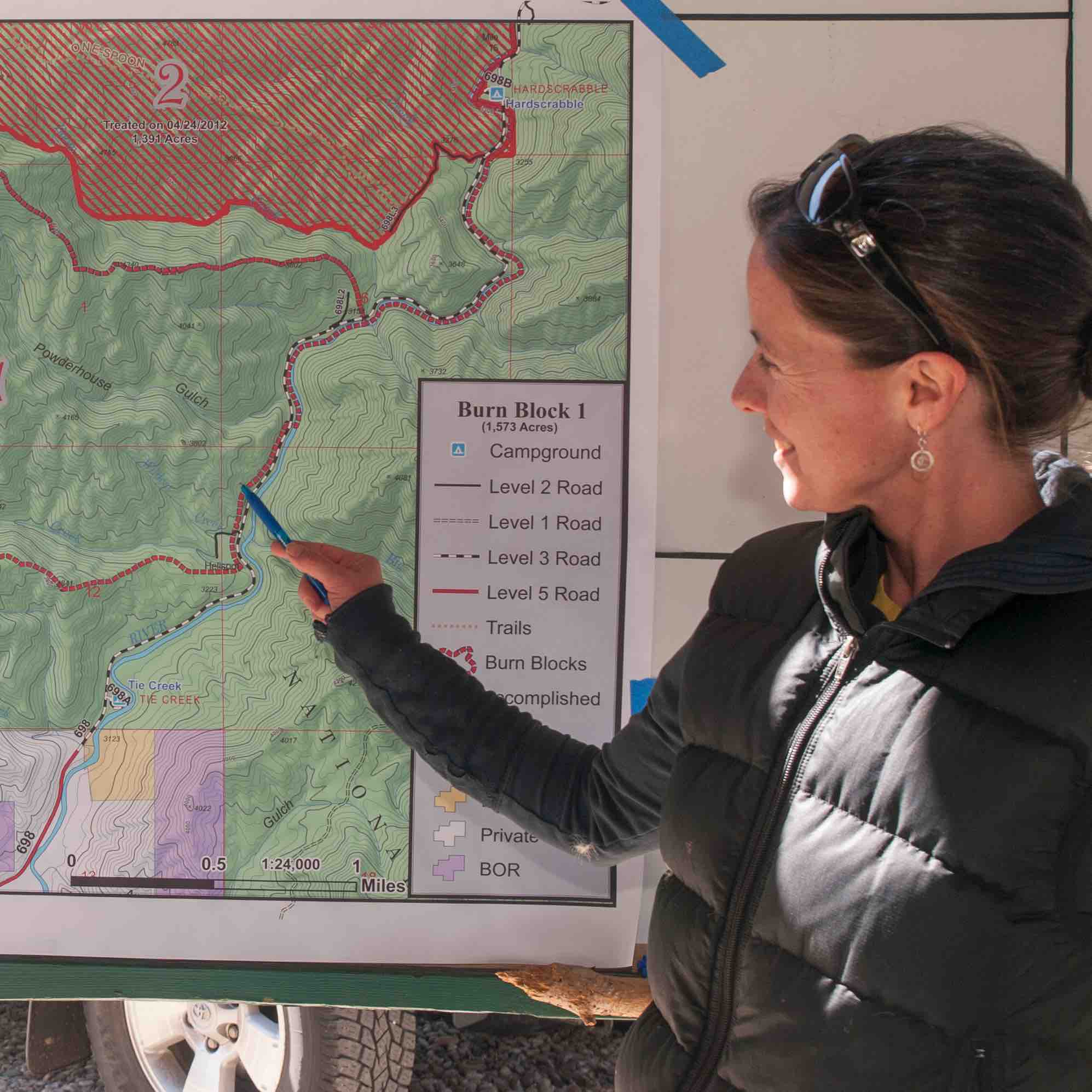 Woman pointing out a fire polygon on a wall map.